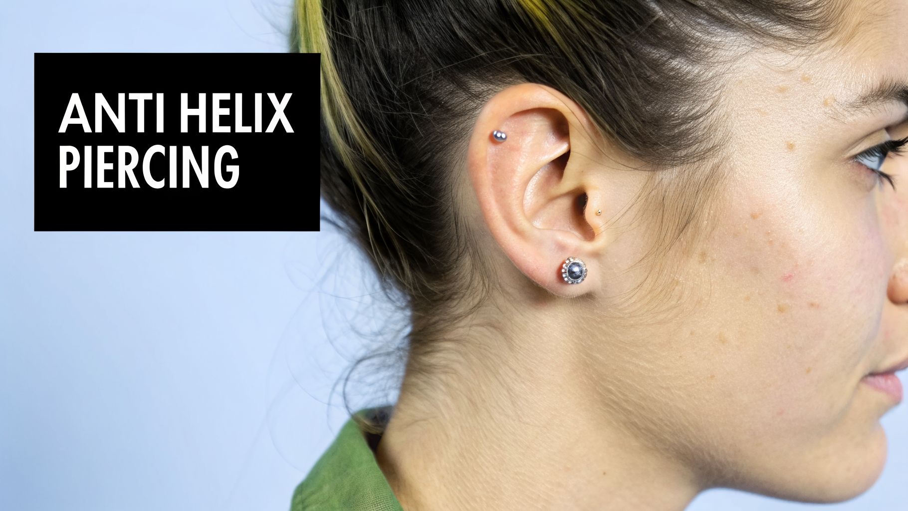 A close-up of a person's ear showcasing an anti-helix piercing and other ear jewelry.