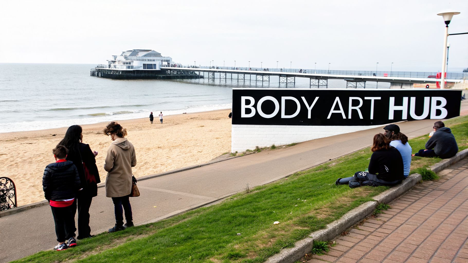 A group of people by a beach and pier, next to a large 'BODY ART HUB' sign.