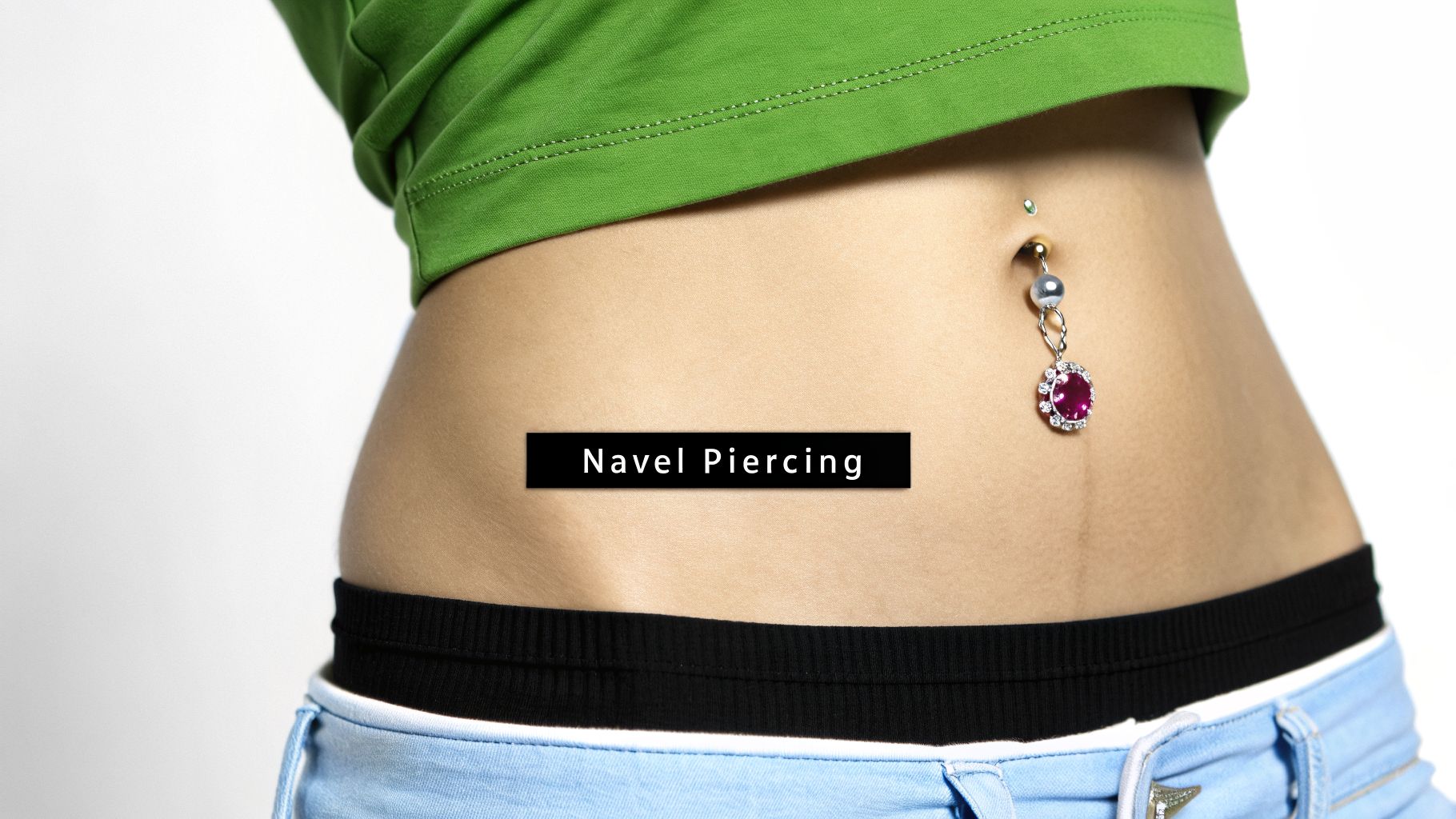 Close-up of a person's belly with a decorative navel piercing featuring a pink gemstone.