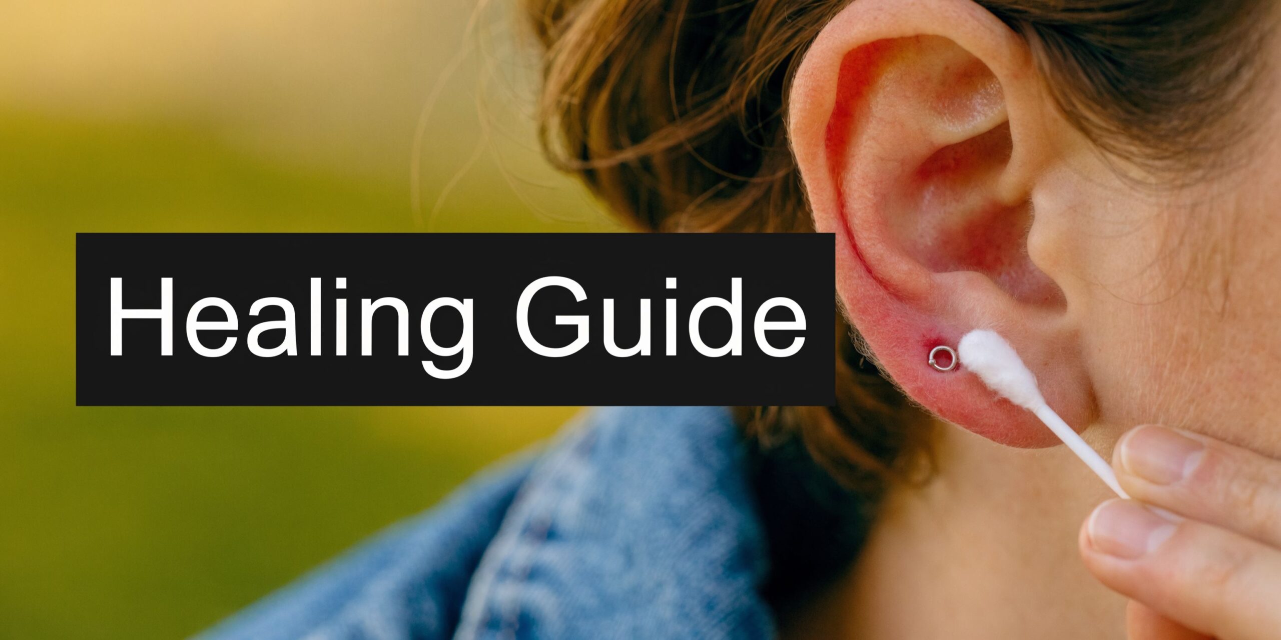 A close-up view of a person cleaning an inflamed helix ear piercing with a cotton swab.