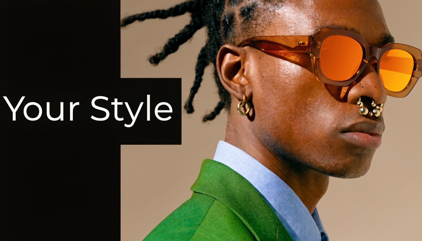 A close up portrait of a man wearing orange sunglasses and stylish gold septum and ear jewelry.