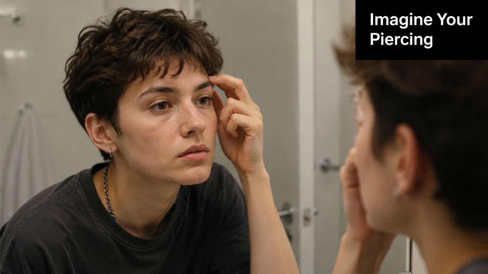 A person with short hair examining their eyebrow in the mirror to visualize a potential piercing.