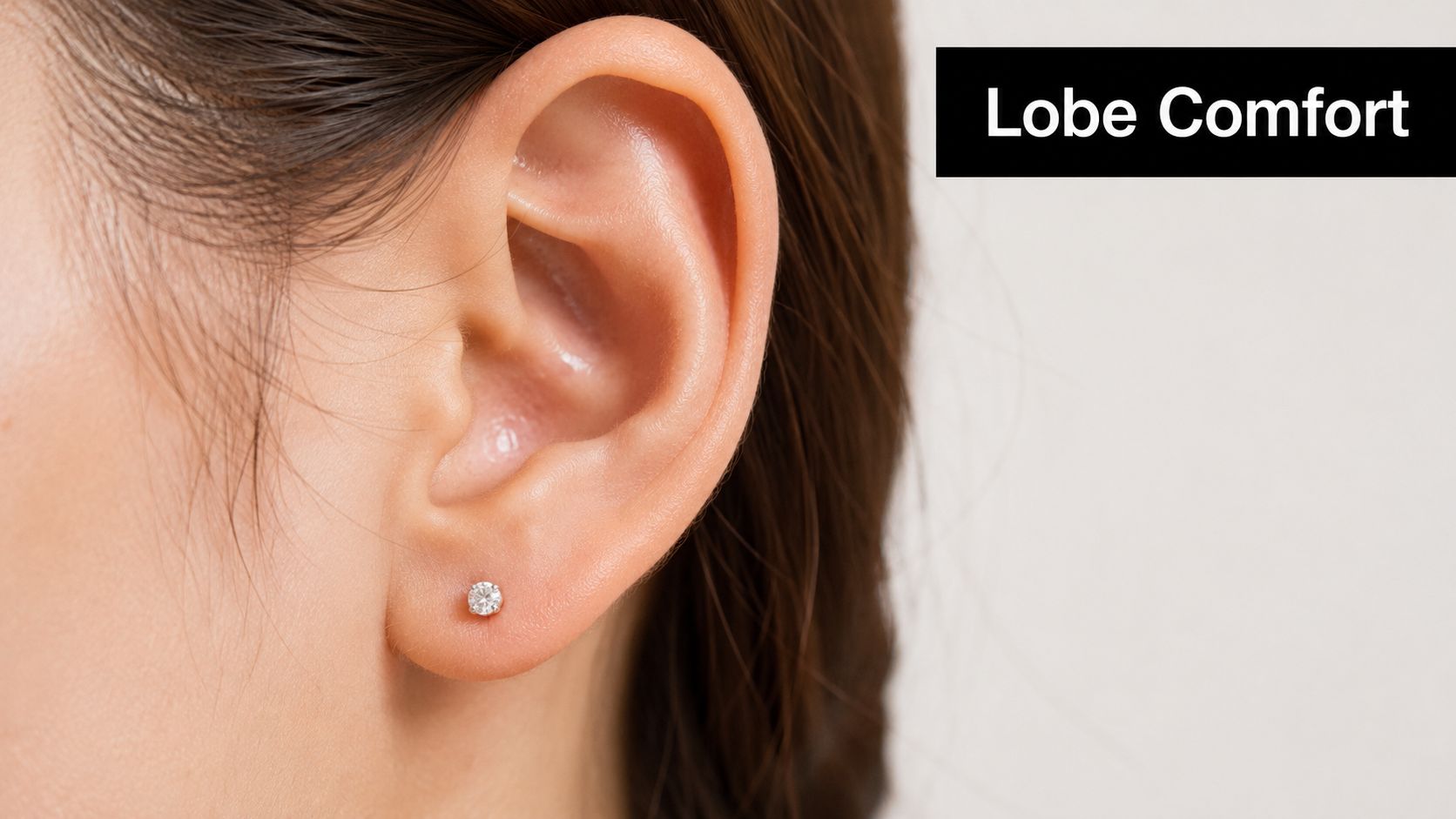 A close-up view of a woman's ear featuring a comfortable and minimalist diamond stud piercing.