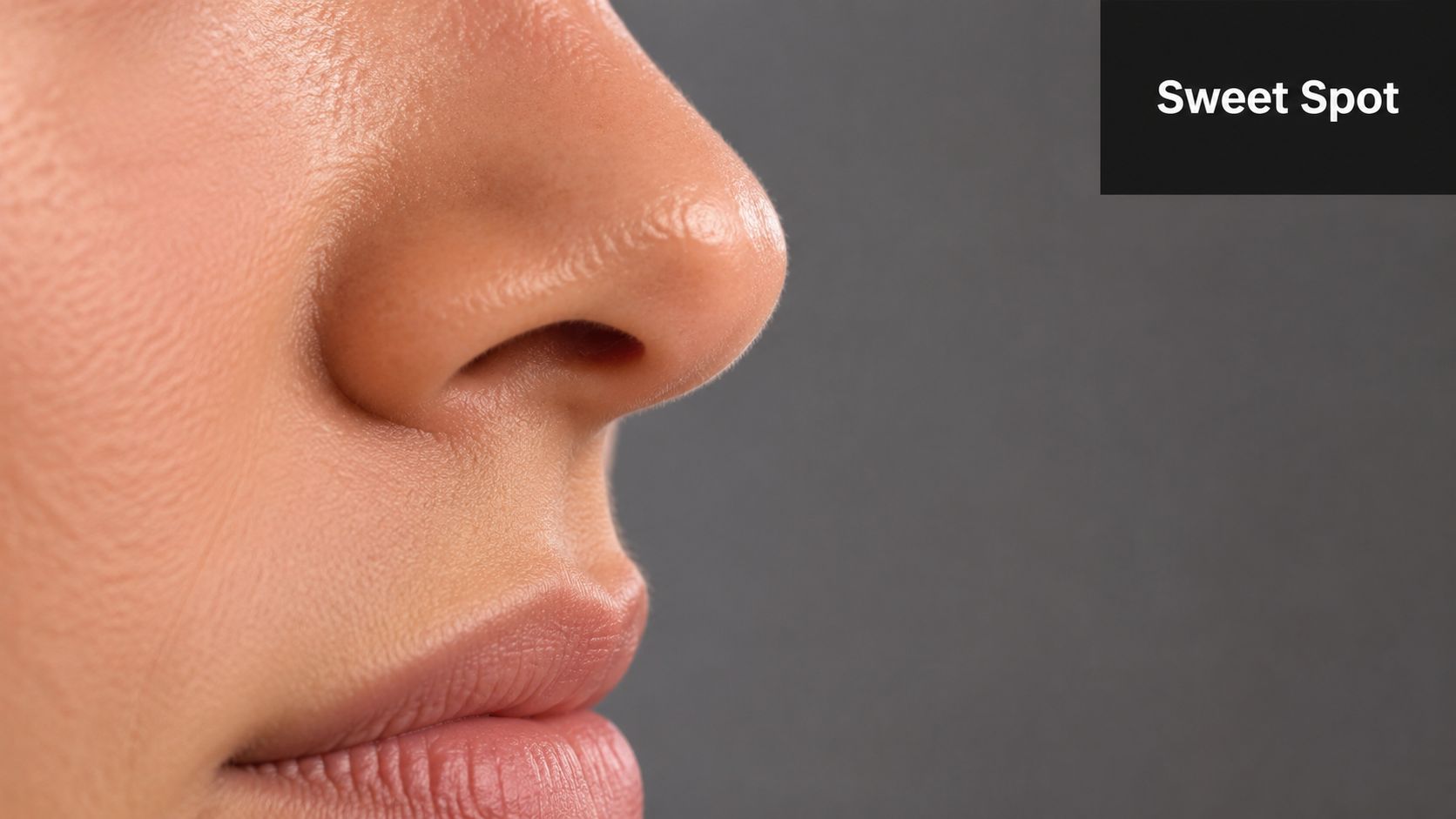 A close-up side profile view of a person's nose and lips against a dark grey background.