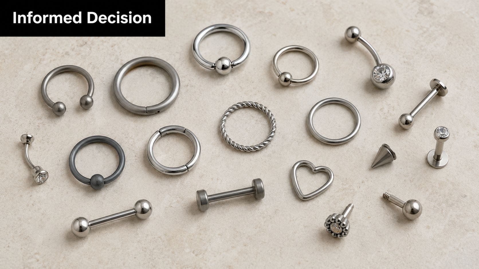 A flat lay collection of various surgical steel and titanium body piercing jewelry pieces on a beige background.