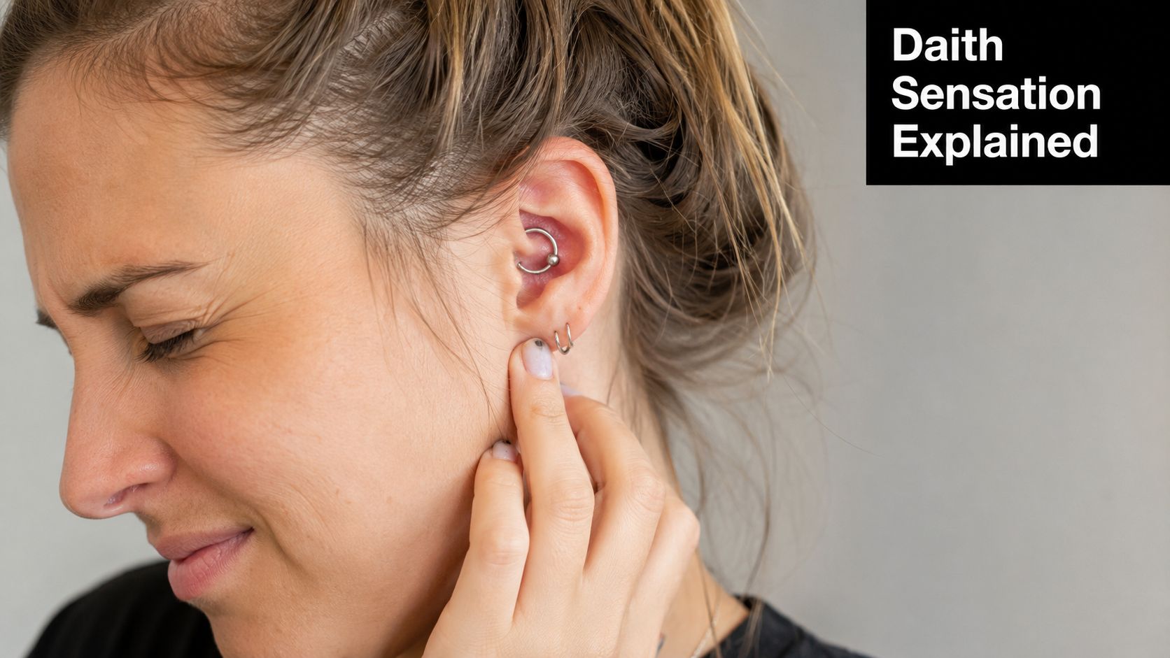 A young woman touching her ear lobe while experiencing discomfort from a new daith piercing.