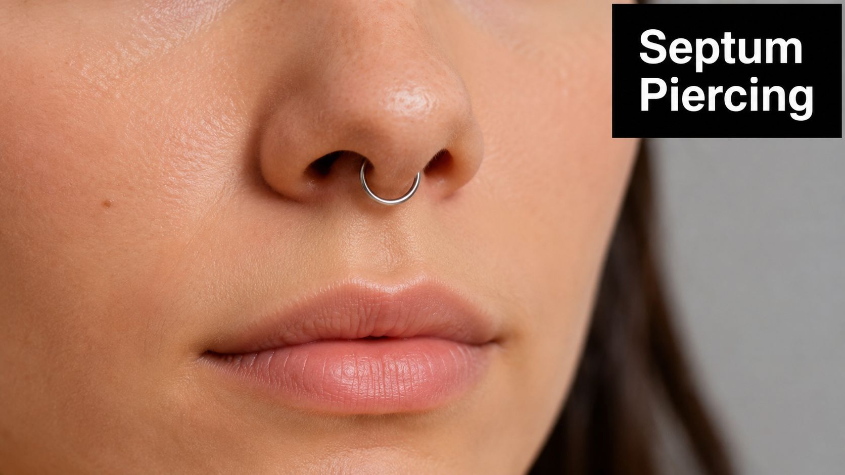 Close-up of a person's nose showing a minimalist silver hoop ring in a septum piercing.