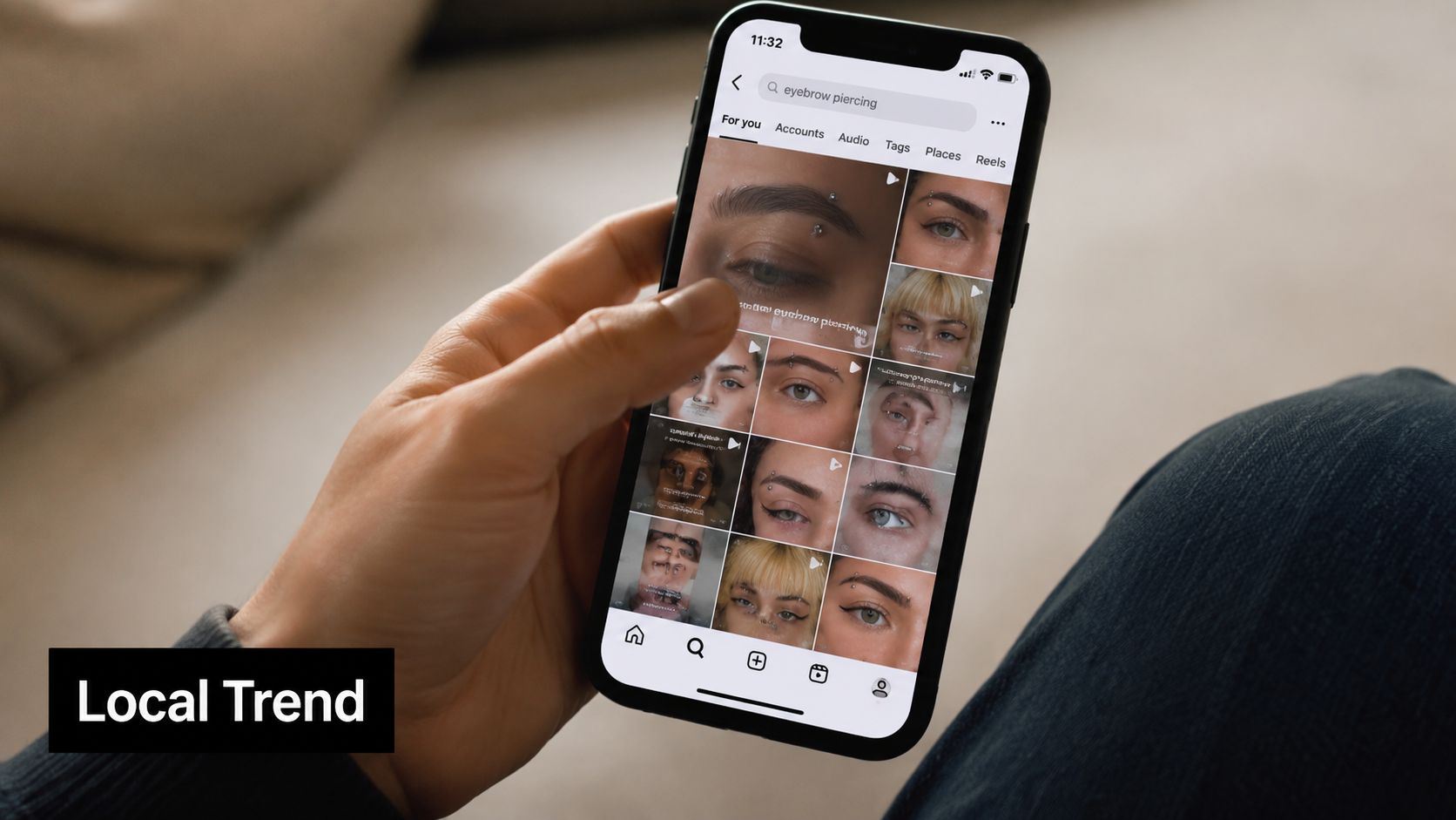 A close-up view of a person holding a smartphone showing an Instagram search for eyebrow piercings.
