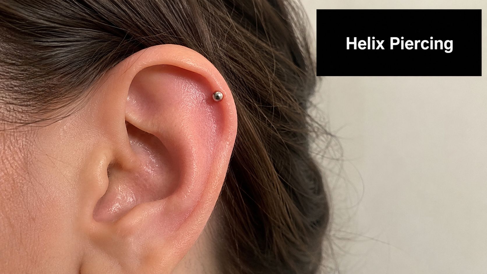 A close-up view of a person's ear showcasing a single metallic stud in a helix piercing.