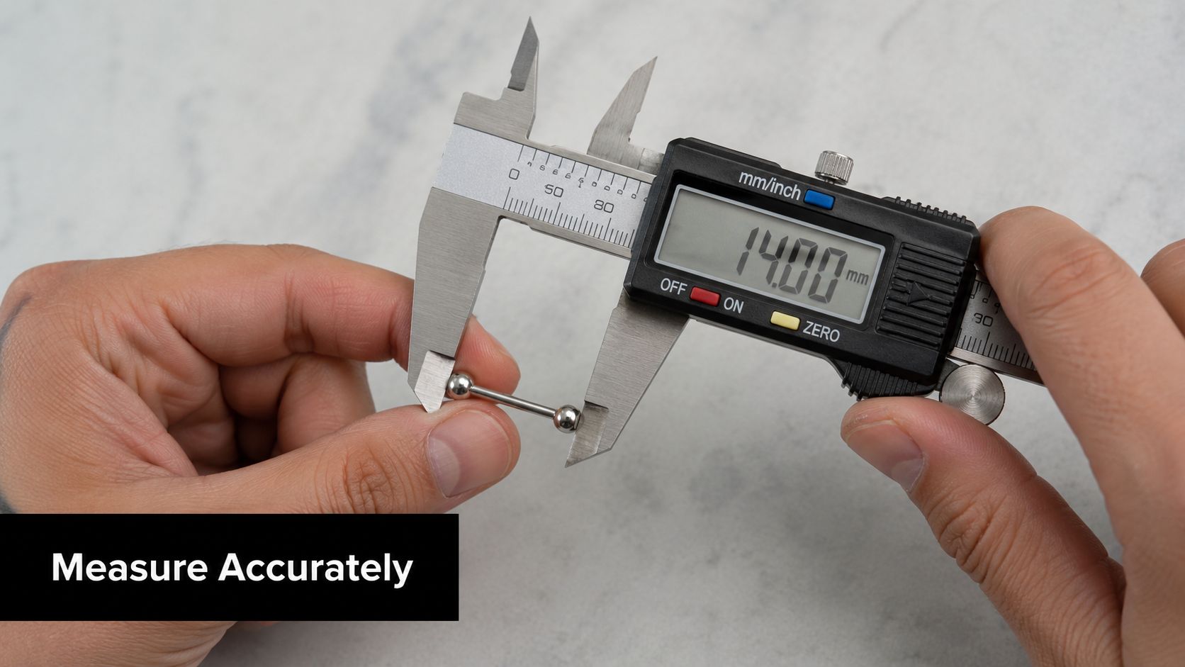A close-up shot of a digital caliper measuring the length of a small metal piercing barbell.