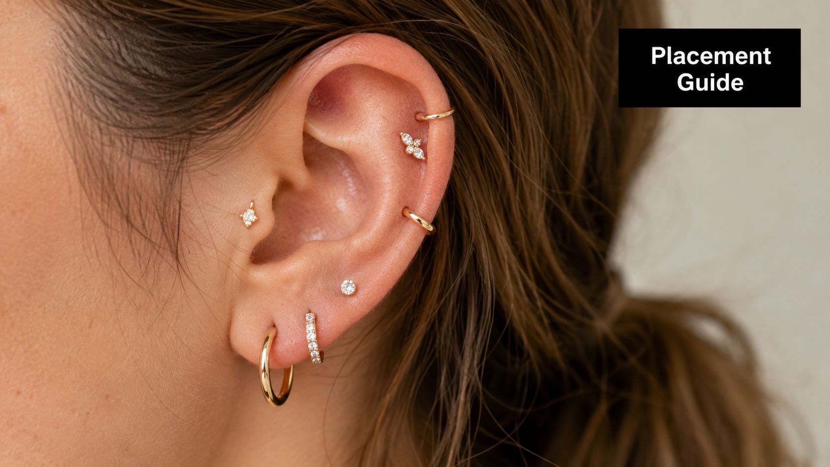 Close-up of a person's ear displaying various gold and diamond piercing jewelry in multiple earlobe and cartilage locations.