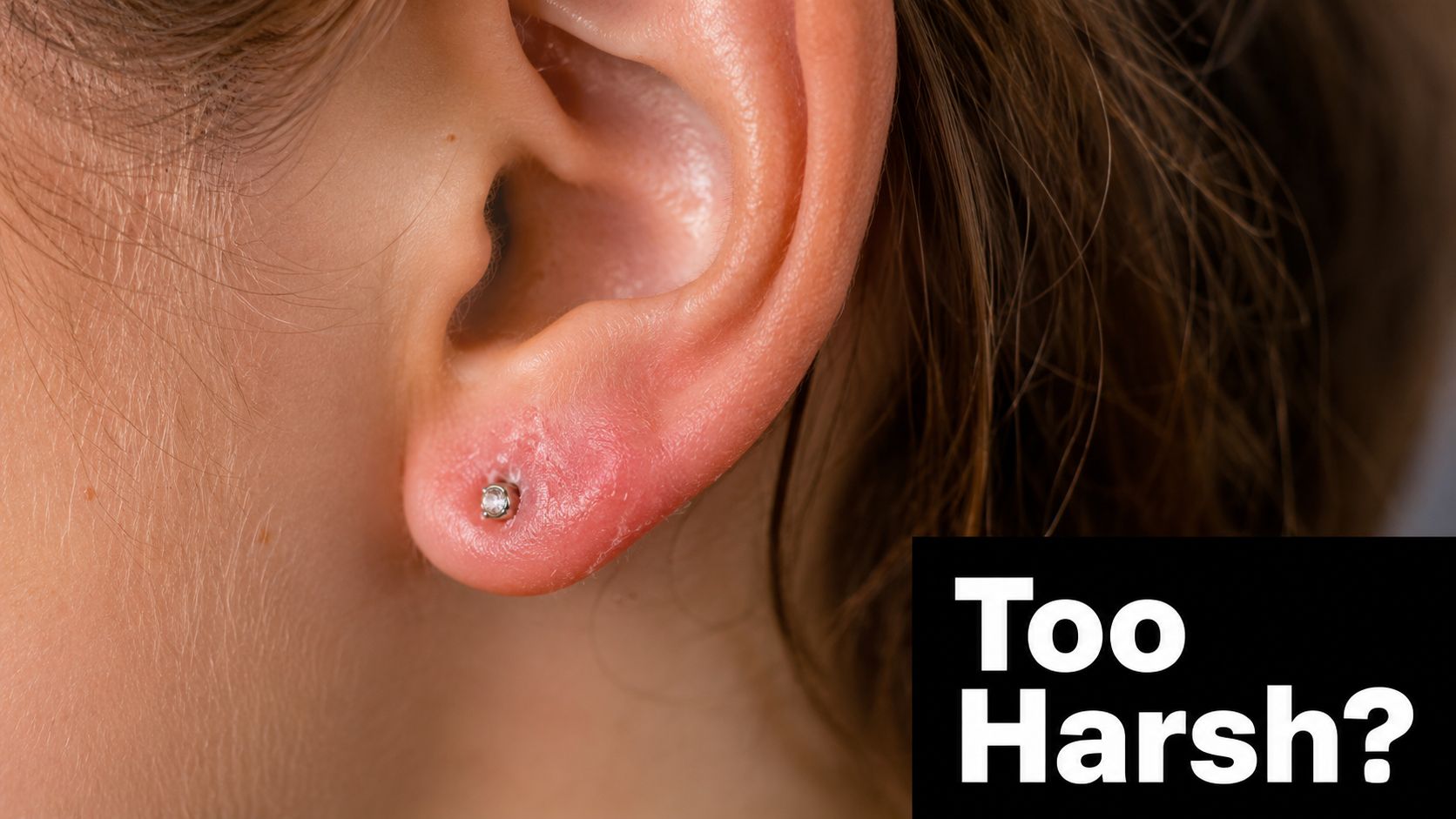 A close-up view of a red, irritated earlobe with a piercing, questioning if aftercare is too harsh.
