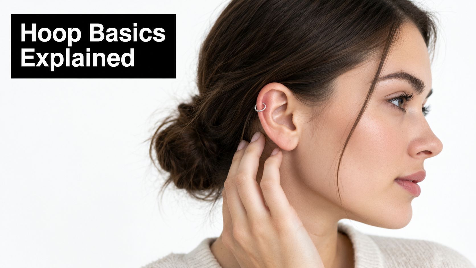 A young woman wearing a delicate silver hoop earring in her upper ear cartilage piercing.