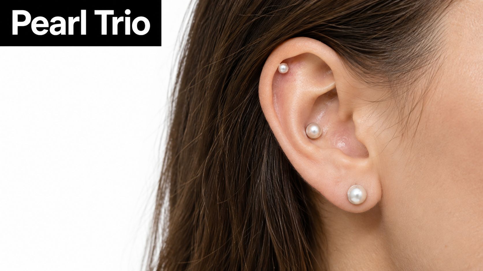 A close-up view of a woman's ear adorned with three elegant pearl stud piercings.