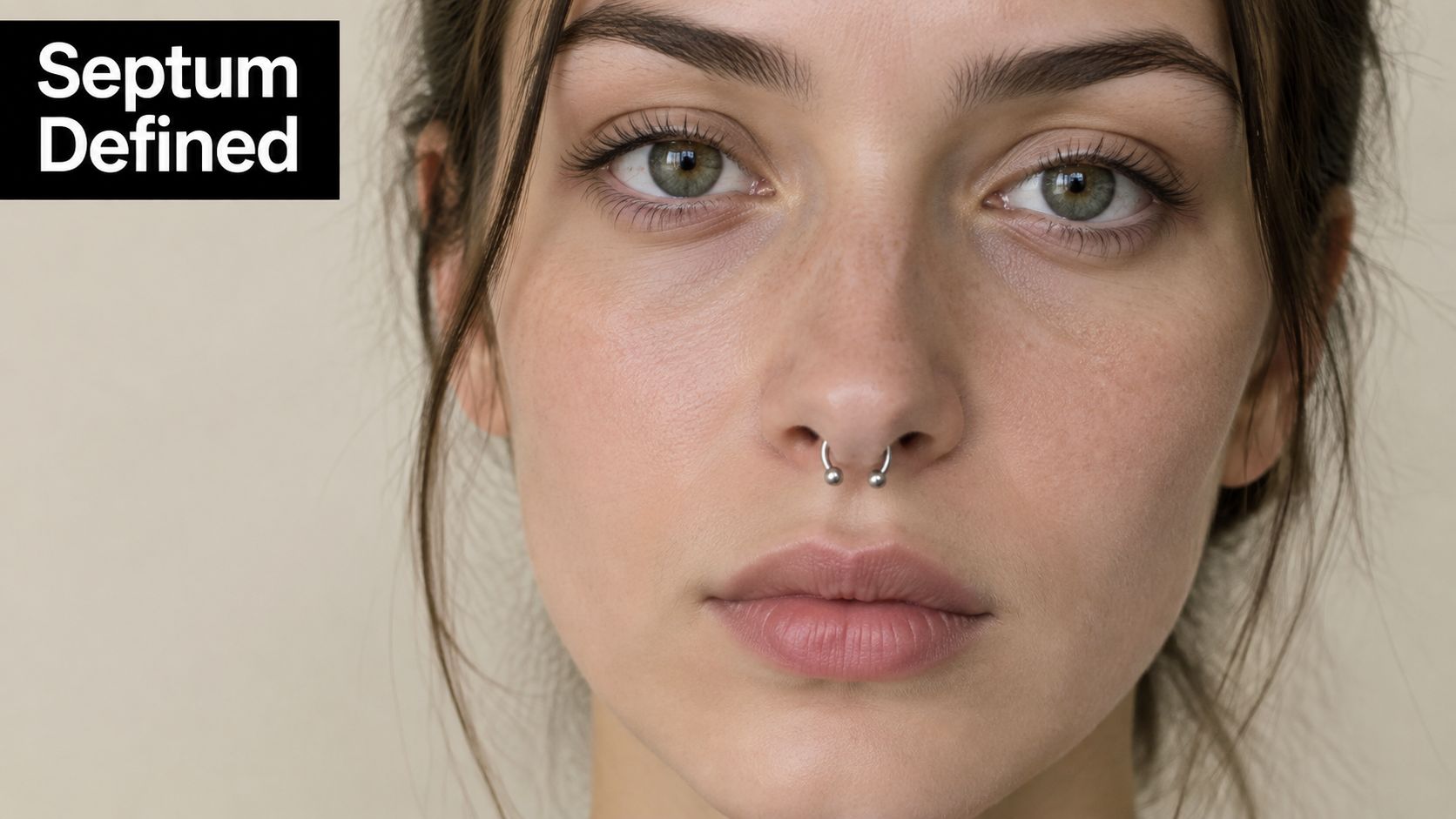 A close-up portrait of a young woman featuring a subtle and stylish silver septum piercing.