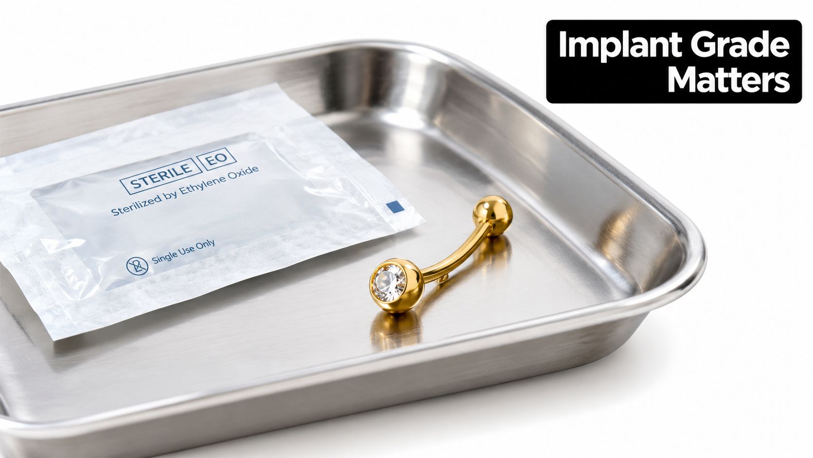 A gold navel piercing jewelry piece resting in a stainless steel tray with a sterile pouch.